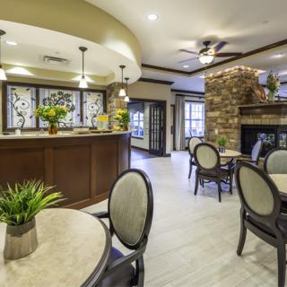 A stylish lounge area featuring modern seating, a kitchen counter, and a stone fireplace.