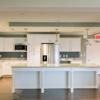A modern kitchen with white cabinets, a large island counter, and stainless steel appliances.