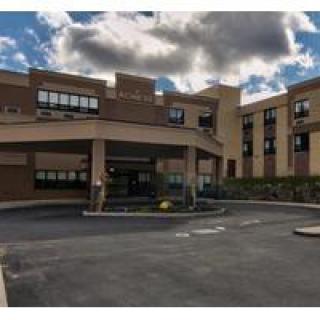 A hospital building with an entrance area and cloudy skies above.