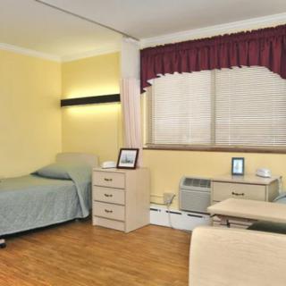 A tidy bedroom with two beds, a desk, and an air conditioner by the window.