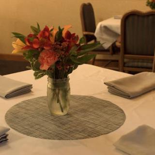 A cozy dining table setup featuring a floral centerpiece in a glass vase.