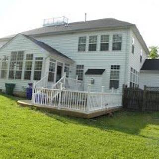 A two-story white house with a spacious backyard and a wooden deck.