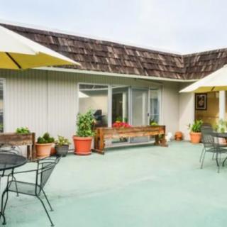 A cozy outdoor patio with tables, chairs, and umbrellas surrounded by potted plants.