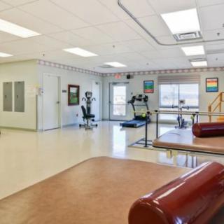 A spacious rehabilitation room equipped with physical therapy tools and exercise machines.