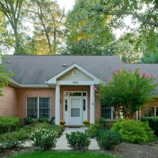 A charming brick house with a well-maintained garden and trees surrounding the property.