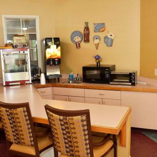 A cozy kitchen area with a counter, chairs, and various appliances including a microwave and popcorn machine.