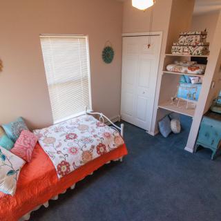 A cozy children's bedroom with colorful bedding and neatly arranged shelves.