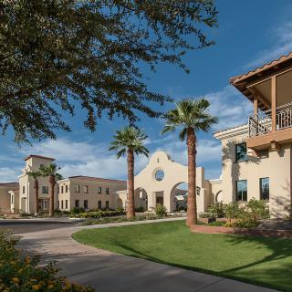 A scenic view of Spanish-style architecture with palm trees and a clear blue sky.