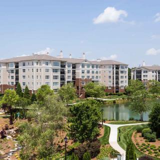 Scenic view of apartment buildings surrounded by lush greenery and a tranquil pond.