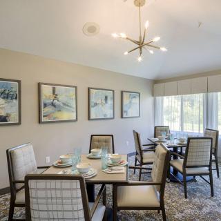 A well-decorated dining room featuring elegant furniture, wall art, and a modern chandelier.