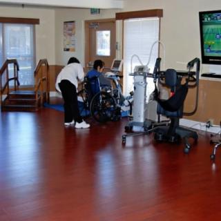 A rehabilitation room equipped with exercise machines and therapists assisting patients.