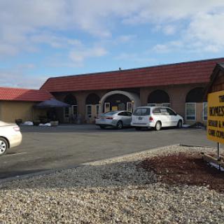 A commercial building with a parking lot on a cloudy day.