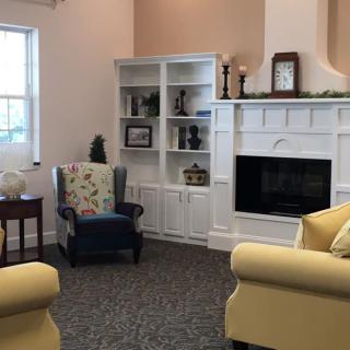 A cozy living room with a fireplace, bookshelves, and comfortable seating.