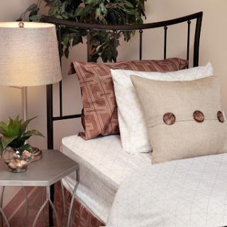 A cozy and stylish bedroom setup featuring decorative pillows, a modern lamp, and a small plant.