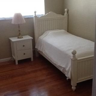 A simple bedroom with a single bed and nightstand.