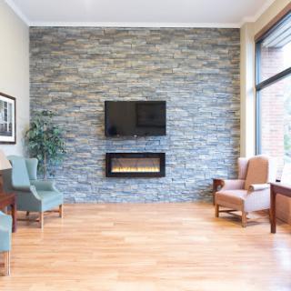 A modern living room featuring a stone accent wall, a fireplace, and comfortable seating.