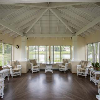 A spacious sunroom with large windows and wicker chairs, offering a relaxing view of the outdoors.