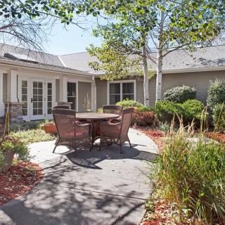 A serene courtyard with patio furniture surrounded by lush greenery on a sunny day.