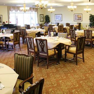 An elegant dining room with neatly arranged tables and chairs, decorated with warm lighting.