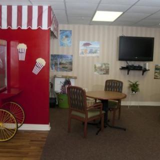 A cozy waiting room with an ice cream theme, featuring a small seating area and a television.