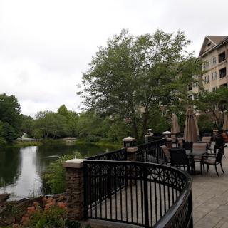 A serene lakeside view featuring lush greenery and outdoor seating.