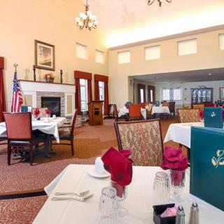 Elegant dining area with neatly arranged tables and chairs, featuring a cozy fireplace and an American flag.