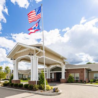 A building entrance with American and Ohio state flags flying under a cloudy sky.