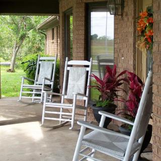 A cozy porch with white rocking chairs and potted plants.