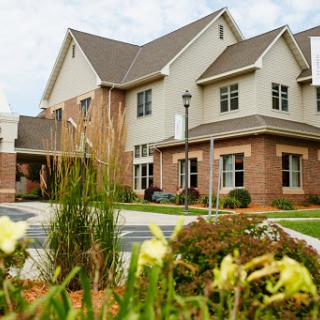 A modern residential building surrounded by greenery and flowers.