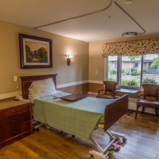 A well-appointed patient room in a healthcare facility, featuring a hospital bed and comfortable seating by the window.