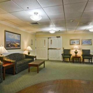 A cozy waiting room with a sofa, chairs, and decorative paintings on the walls.