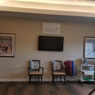 A waiting room area with chairs, a television, and framed artwork on the walls.