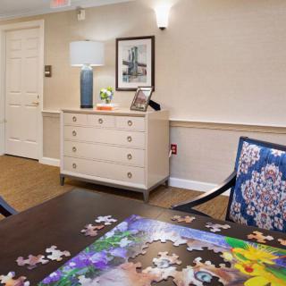 A cozy room featuring a dresser with decorative items and a partially completed puzzle on the table.
