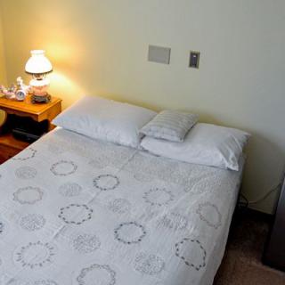 A cozy bedroom with a neatly made bed, soft lighting from a lamp on the nightstand, and simple decor.