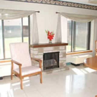 A bright living room featuring a fireplace, large windows with curtains, and a chair next to a vase of flowers.