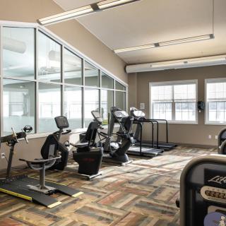 A well-lit gym featuring treadmills and stationary bikes.