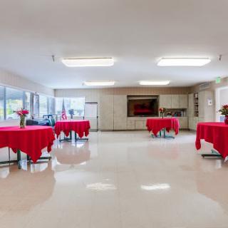 A spacious event room set up with tables covered in red cloth, ideal for gatherings or celebrations.