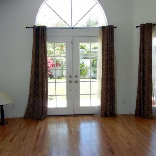 A bright living room with large glass doors and hardwood flooring.