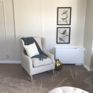 A cozy corner with an armchair and wall art in a minimalist living room.