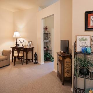 A cozy living room interior featuring a small desk, a lamp, and decorative items.
