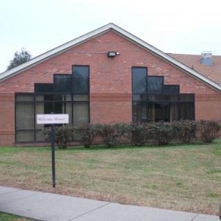 A brick building with large windows and a neatly trimmed lawn.