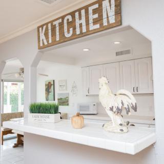 A modern farmhouse-style kitchen with a rustic 'KITCHEN' sign and decorative elements.