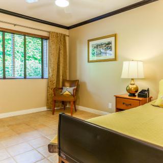 A cozy bedroom with warm lighting and tasteful decor, featuring a comfortable chair by the window.