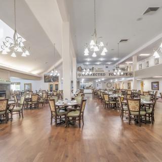 A spacious and elegantly designed dining hall with numerous tables and chandeliers.