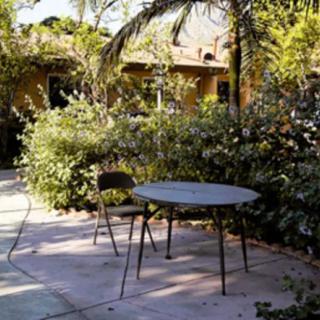 A peaceful garden patio with a round table and chair surrounded by lush greenery.