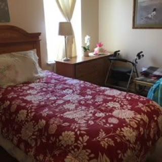 A cozy bedroom with a floral bedspread and a walker nearby.
