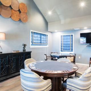 A cozy living room featuring a poker table, comfortable seating, and modern decor.