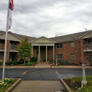 A brick residential building with an entrance and flags on a cloudy day.