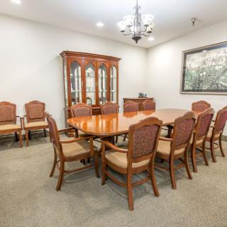 A spacious and elegantly designed meeting room featuring a large wooden table surrounded by comfortable chairs, perfect for formal discussions and gatherings.
