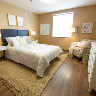 A cozy and well-lit bedroom featuring a comfortable bed, stylish decor, and warm colors.